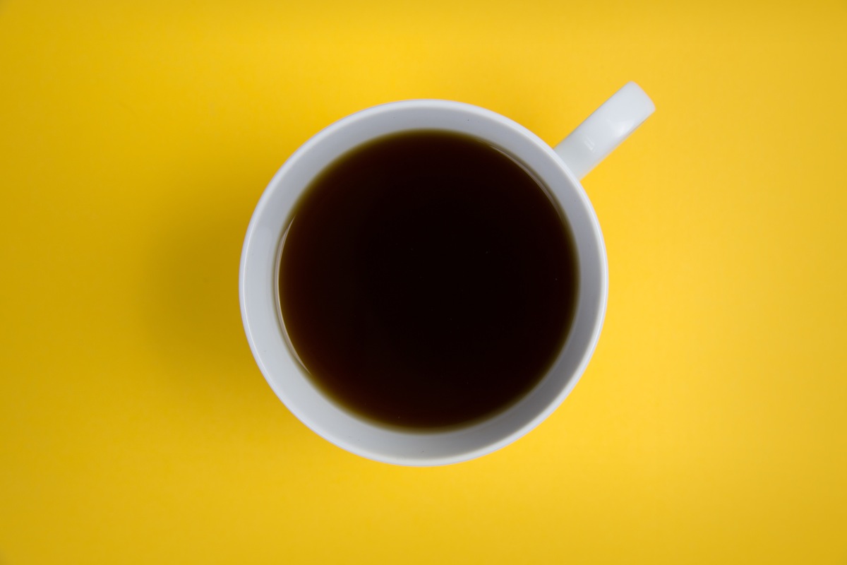 Top down view of coffee mug on a yellow surface