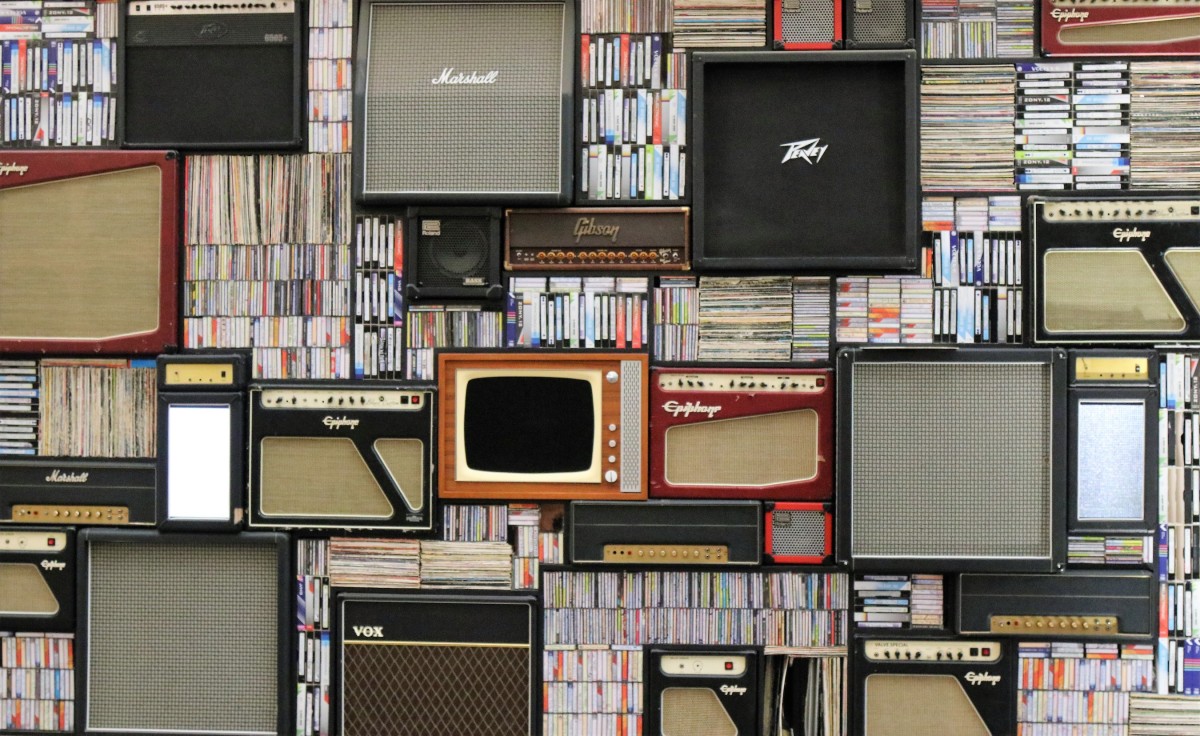 Assorted music amps, records, tapes, books, and televisions on a wall