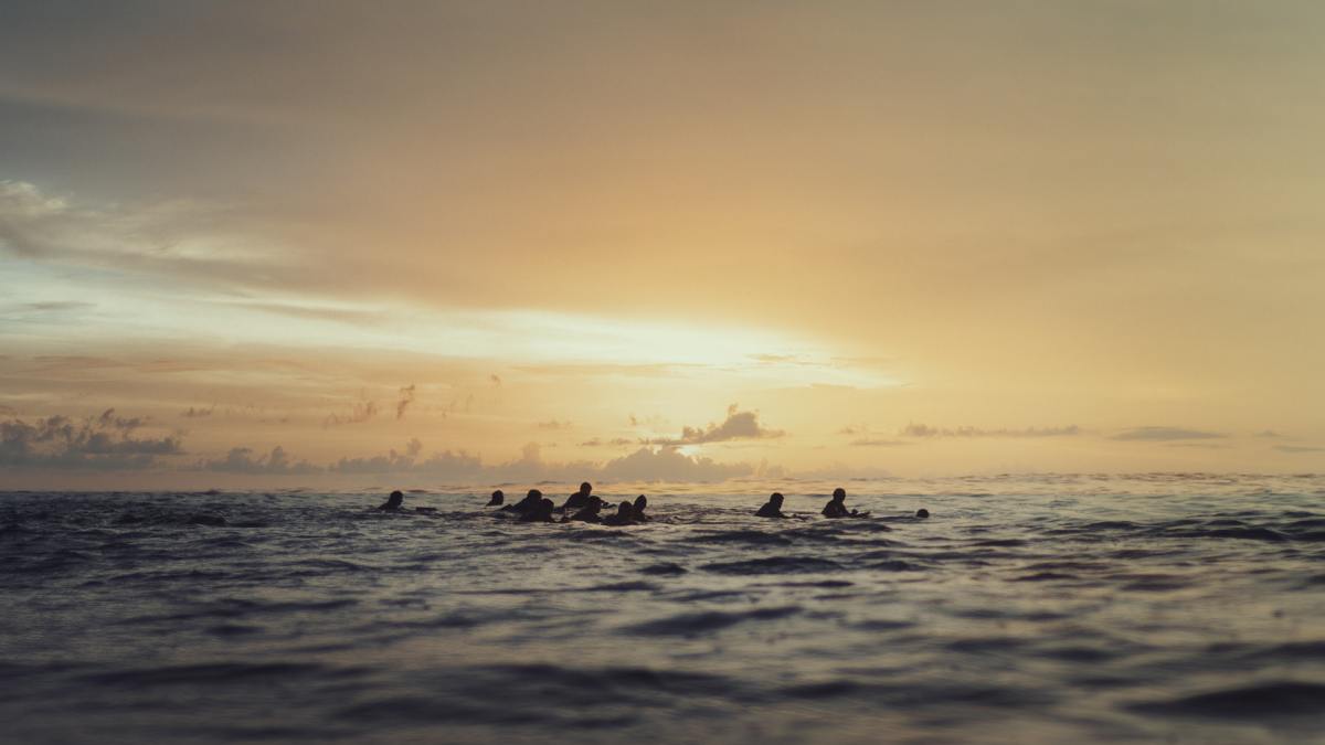 A group of people floating in open water at dusk